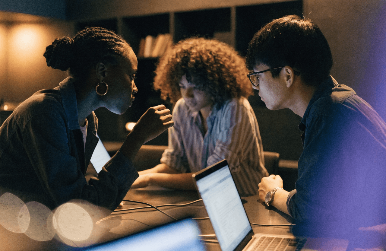 A small team collaborating around laptops in a modern studio